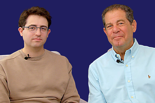Two men, one with dark brown hair and one with light brown hair, sitting next to one another.